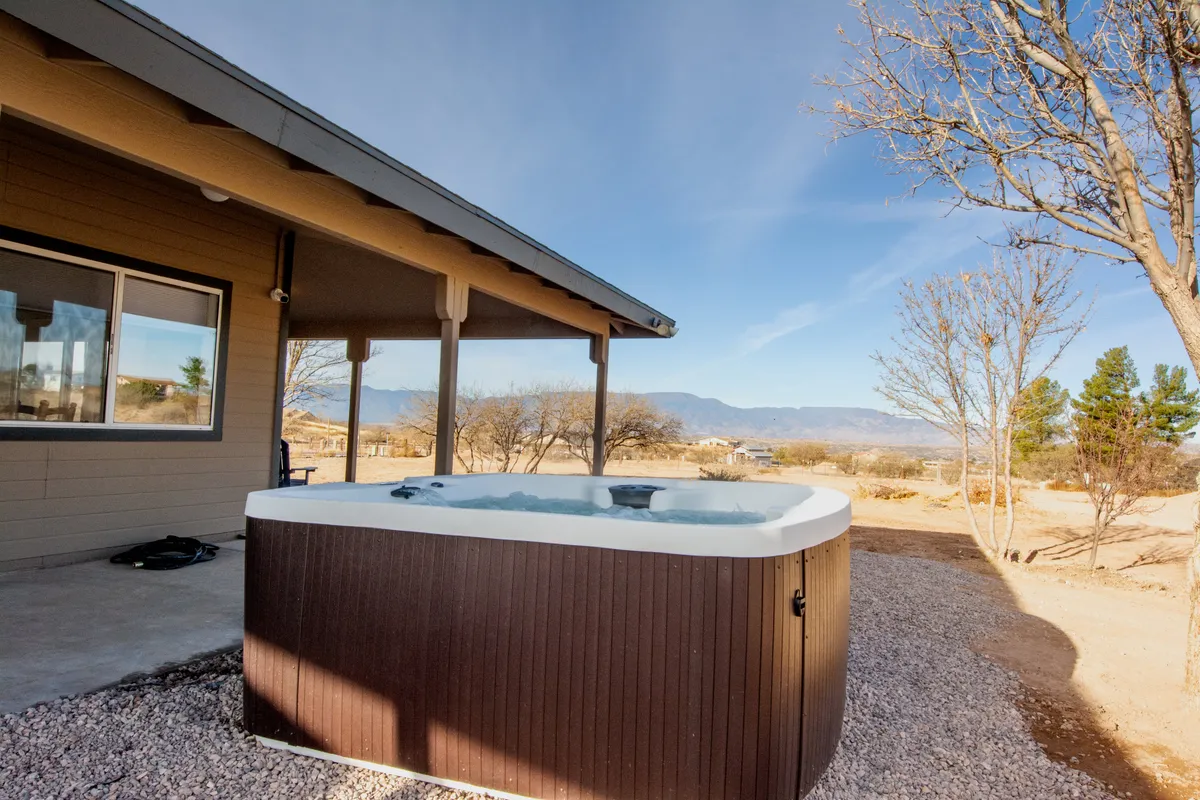 This image features an inviting hot tub set on a deck with expansive mountain views in the background. The scene is tranquil, capturing the hot tub as a focal point, perfect for relaxation under the sky, with the natural beauty of the landscape stretching out beyond.