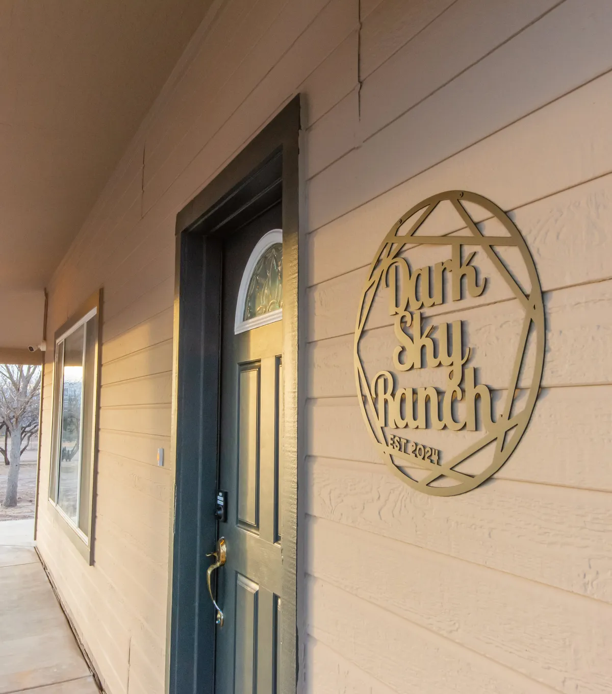 An inviting view of the house's front door and porch area, adorned with the distinctive Dark Sky Ranch sign. This welcoming entry at dusk suggests the transition from wine country explorations back to an intimate home environment.